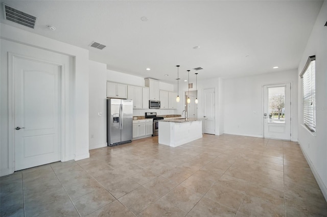 kitchen with stainless steel appliances, a center island with sink, visible vents, and white cabinets