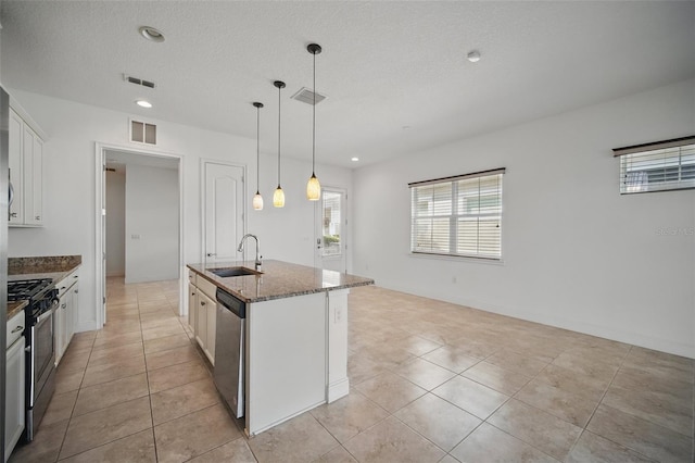 kitchen with appliances with stainless steel finishes, dark stone counters, visible vents, and a sink