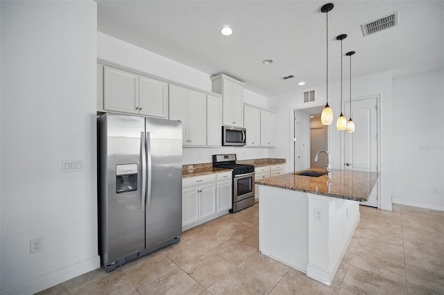 kitchen with dark stone countertops, visible vents, stainless steel appliances, and a sink