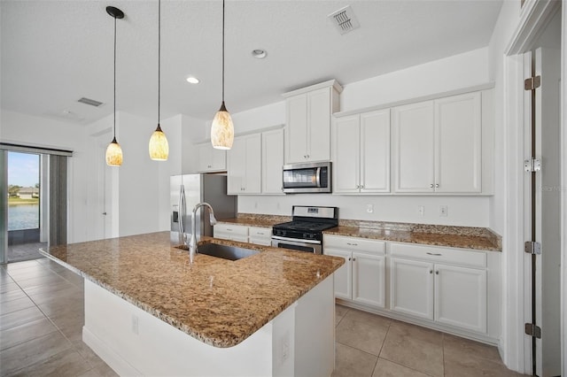 kitchen featuring a center island with sink, visible vents, appliances with stainless steel finishes, white cabinetry, and a sink