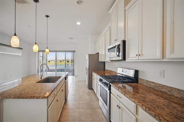 kitchen with appliances with stainless steel finishes, a kitchen island with sink, light tile patterned flooring, a sink, and recessed lighting