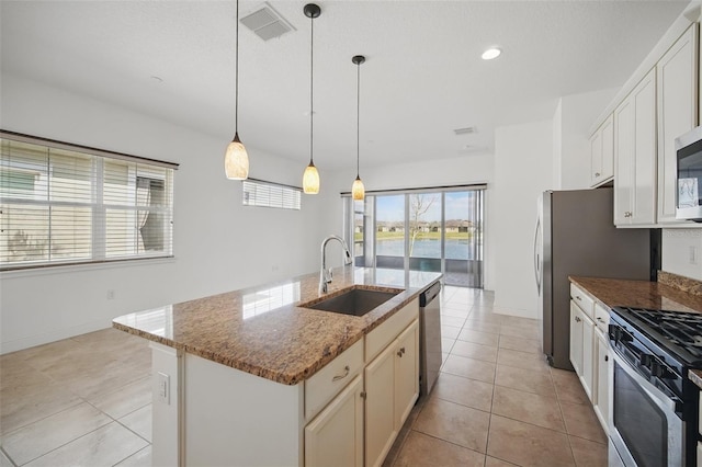 kitchen with light tile patterned floors, visible vents, appliances with stainless steel finishes, dark stone countertops, and a sink