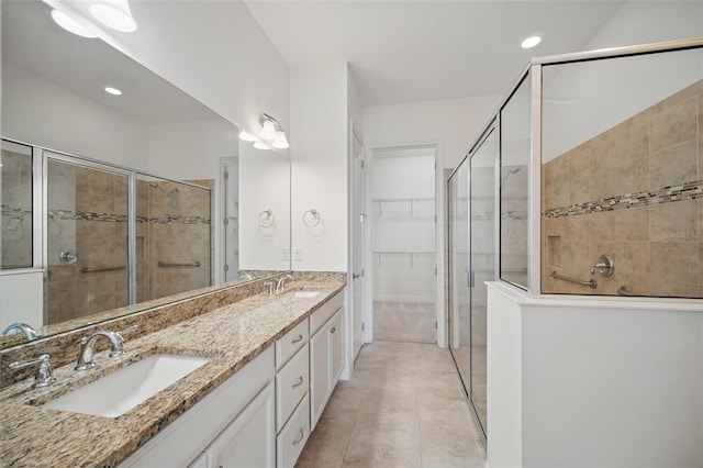 full bath with double vanity, a shower stall, a sink, and tile patterned floors