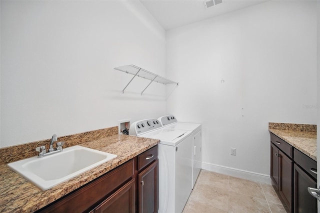 clothes washing area featuring a sink, visible vents, baseboards, cabinet space, and washing machine and clothes dryer