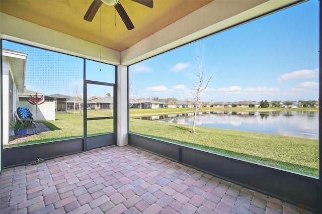 unfurnished sunroom with a water view, a residential view, and a ceiling fan