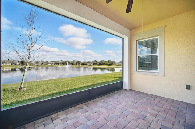 unfurnished sunroom featuring a ceiling fan and a water view