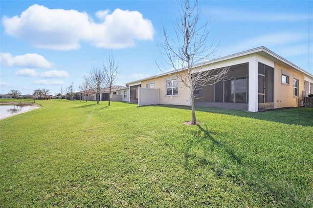 rear view of house with a lawn, a sunroom, and stucco siding