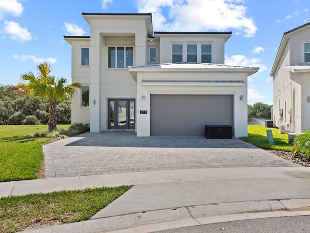 view of front of home with decorative driveway, french doors, an attached garage, and stucco siding