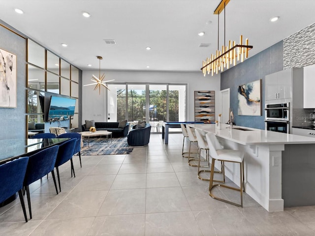 kitchen with light tile patterned flooring, a sink, visible vents, and decorative light fixtures