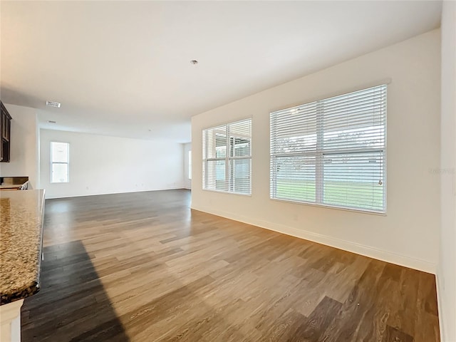 unfurnished living room featuring light wood finished floors, visible vents, and baseboards