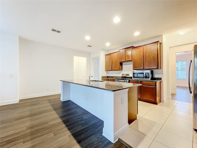 kitchen with recessed lighting, stainless steel appliances, a sink, visible vents, and an island with sink