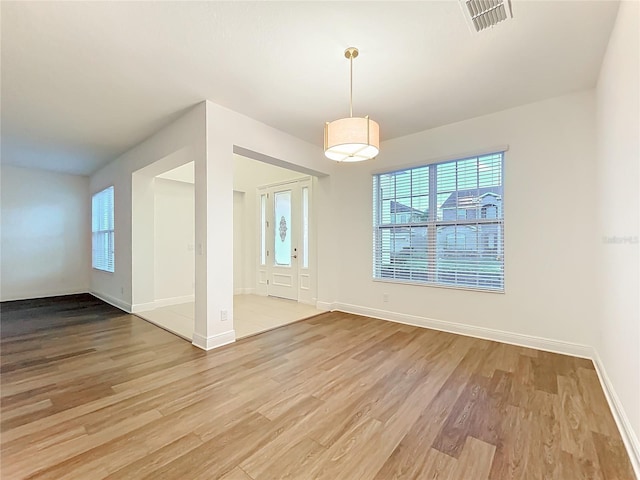 unfurnished dining area featuring light wood-type flooring, baseboards, and visible vents