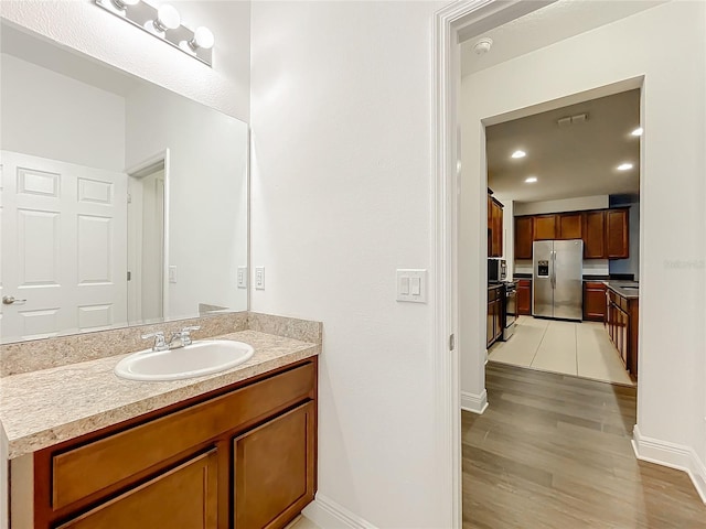 bathroom featuring recessed lighting, wood finished floors, vanity, and baseboards