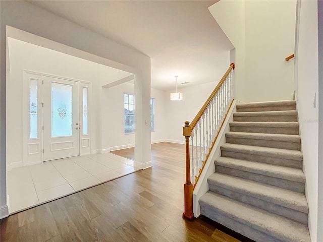 foyer entrance with stairs, wood finished floors, and baseboards