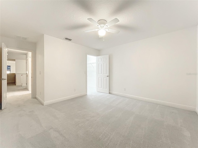 spare room with light carpet, ceiling fan, baseboards, and a textured ceiling