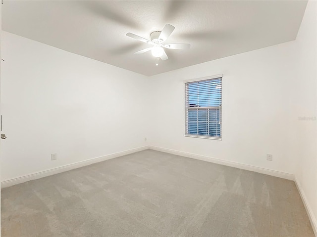 carpeted empty room with baseboards and a ceiling fan