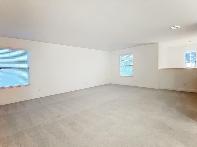 spare room featuring visible vents and light colored carpet