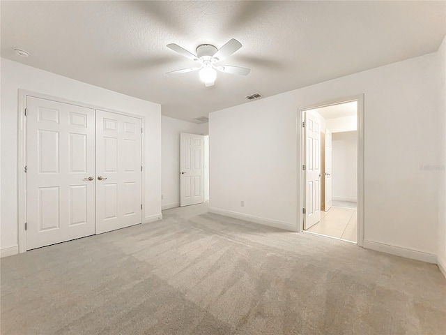 unfurnished bedroom with a textured ceiling, visible vents, a closet, and light colored carpet