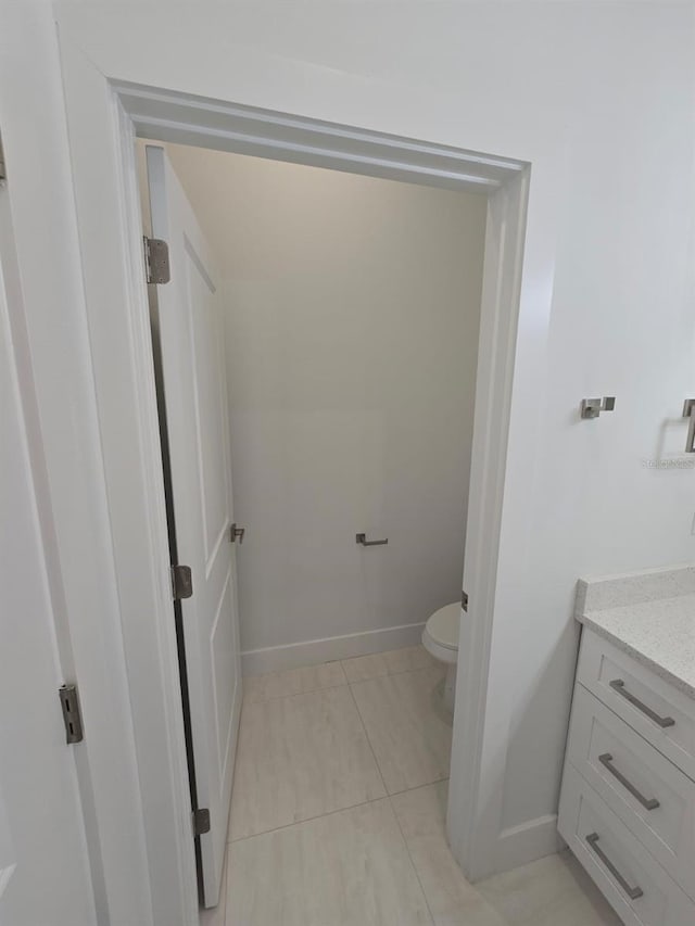 bathroom featuring toilet, vanity, and baseboards