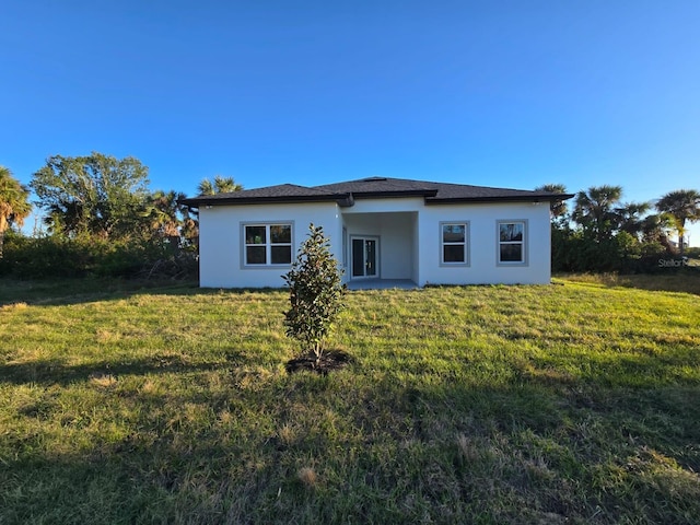 back of property featuring stucco siding and a lawn