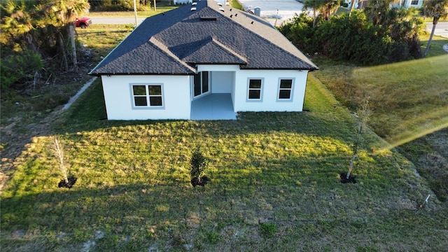 view of front of house with stucco siding, a shingled roof, and a front lawn