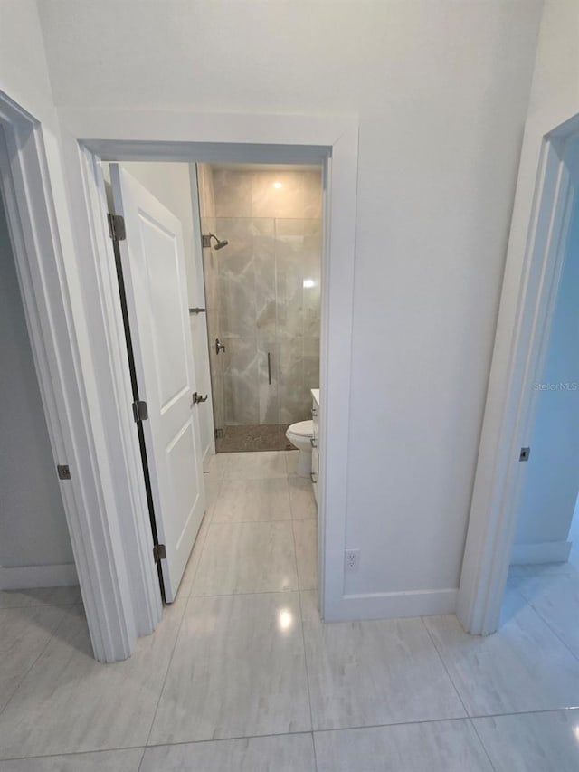 corridor with light tile patterned floors and baseboards