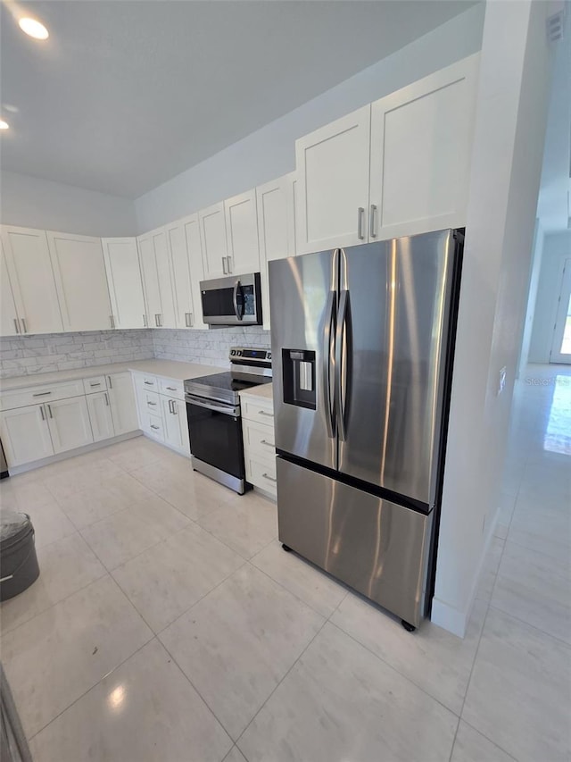 kitchen with stainless steel appliances, white cabinets, decorative backsplash, and light countertops