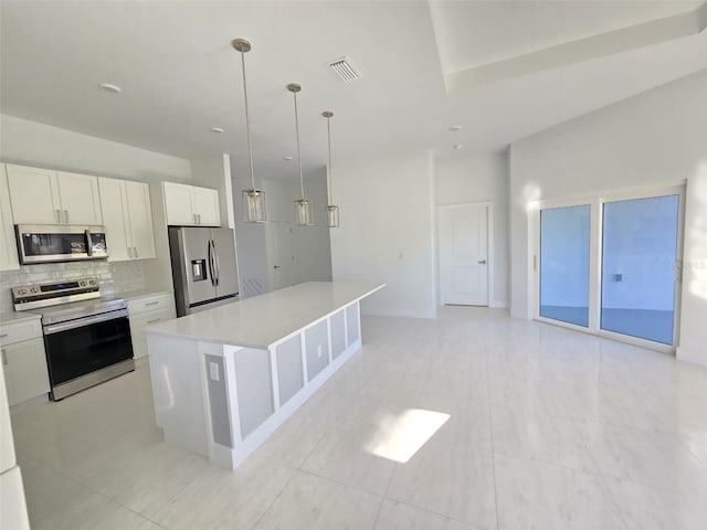 kitchen featuring backsplash, a kitchen island, light countertops, appliances with stainless steel finishes, and white cabinetry