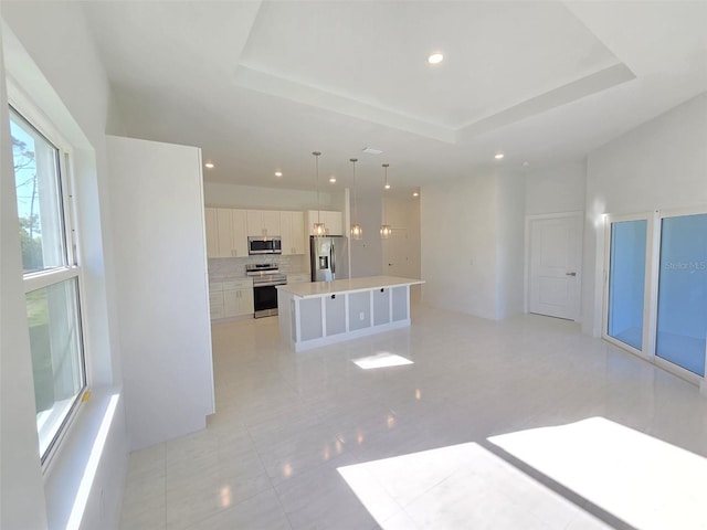 kitchen featuring a tray ceiling, stainless steel appliances, backsplash, and light countertops