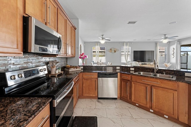 kitchen with marble finish floor, appliances with stainless steel finishes, brown cabinetry, and a sink