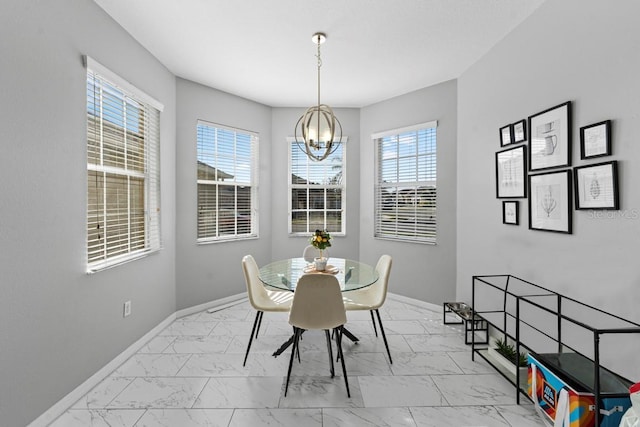 dining room with a chandelier, marble finish floor, and baseboards