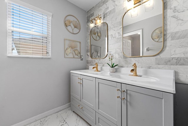 bathroom with marble finish floor, a sink, baseboards, and double vanity