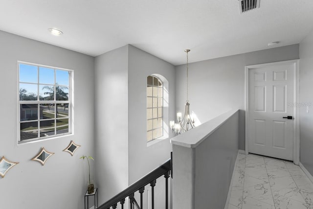 hallway with visible vents, baseboards, an upstairs landing, marble finish floor, and an inviting chandelier