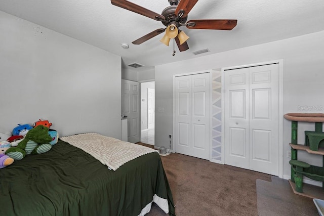 carpeted bedroom with two closets, visible vents, and a ceiling fan