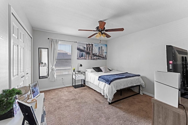 bedroom with baseboards, a ceiling fan, a textured ceiling, carpet floors, and a closet