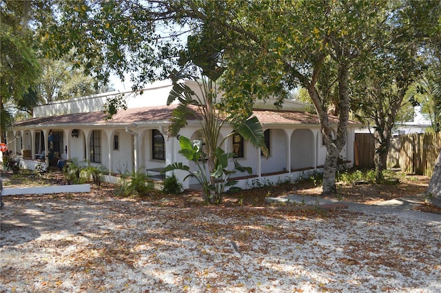 view of front facade with a porch, fence, and stucco siding