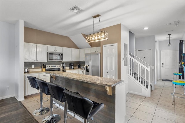 kitchen featuring visible vents, decorative light fixtures, backsplash, white cabinetry, and appliances with stainless steel finishes