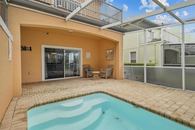 view of pool with glass enclosure and a patio