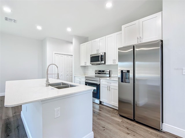 kitchen with light wood-style flooring, stainless steel appliances, a sink, visible vents, and white cabinets