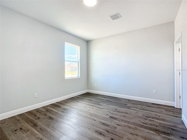 spare room featuring visible vents, baseboards, and wood finished floors