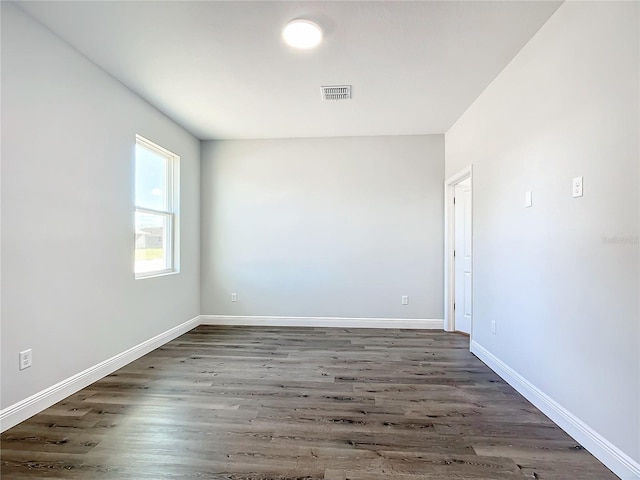 spare room featuring wood finished floors, visible vents, and baseboards