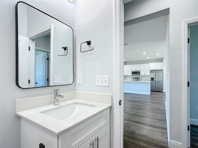 bathroom featuring recessed lighting, vanity, baseboards, and wood finished floors