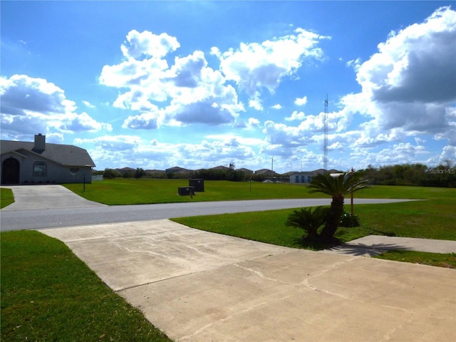 surrounding community featuring a yard and concrete driveway