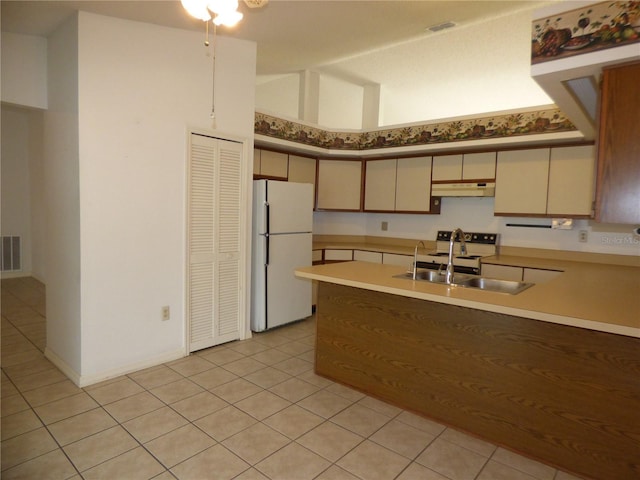 kitchen with light countertops, a sink, a peninsula, white appliances, and under cabinet range hood