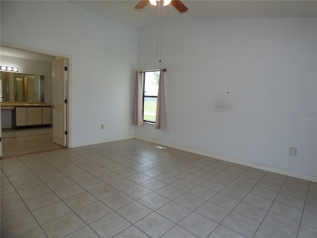 empty room with light tile patterned floors, high vaulted ceiling, a ceiling fan, and baseboards