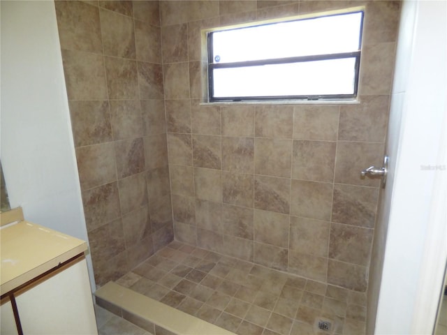 bathroom with a tile shower and vanity