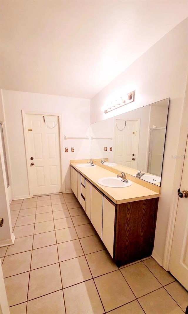 full bath featuring double vanity, tile patterned flooring, and a sink