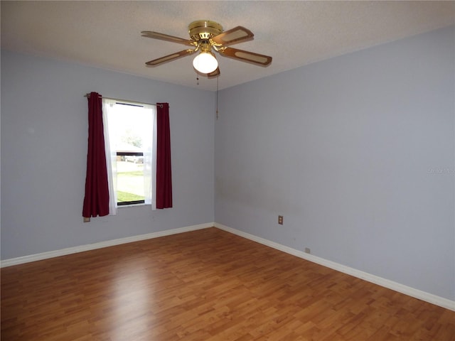 empty room featuring a textured ceiling, light wood-type flooring, a ceiling fan, and baseboards