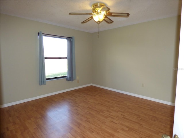 unfurnished room with a textured ceiling, light wood-type flooring, a ceiling fan, and baseboards