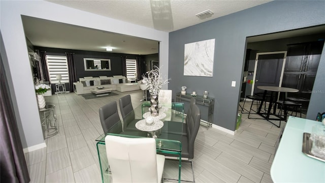 dining area featuring visible vents, baseboards, and a textured ceiling